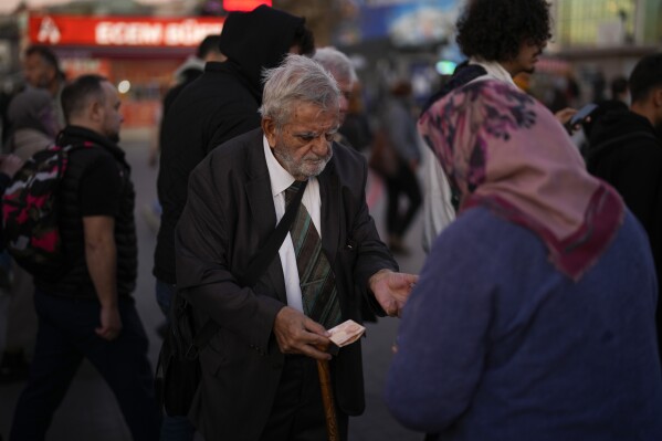 A man purchases food from a street vendor at Kadikoy ferry terminal in Istanbul, Thursday, Nov. 16, 2023. Turkey's central bank delivered another huge interest rate hike on Thursday, Nov. 23, 2023 continuing its effort to curb double-digit inflation that has left households struggling to afford food and other basic goods. (AP Photo/Francisco Seco)