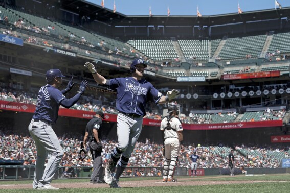 Tampa Bay Rays' Luke Raley, center, celebrates with Christian Bethancourt, left, after hitting an inside-the-park home run during the sixth inning of a baseball game against the San Francisco Giants, Wednesday, Aug. 16, 2023, in San Francisco. (AP Photo/Godofredo A. Vásquez)