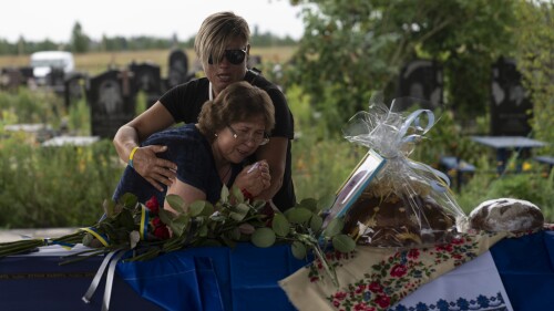 Comforted by Khrystyna Liubymska, top, Zynaida Nedoleshko weeps next to a casket carrying the remains of her nephew, Roman Shadlovskyi, during a reburial service for him in Bucha, Ukraine, Tuesday, July 18, 2023. The Ukrainian armed forces veteran, who was initially buried in a mass grave as an unidentified victim after being killed last year by Russian troops, received a reburial Tuesday after a DNA test confirmed his identity. (AP Photo/Jae C. Hong)