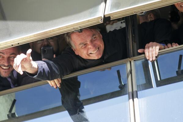 Brazil's former President Jair Bolsonaro waves to supporters at the Liberal Party's headquarters in Brasilia, Brazil, Thursday, March 30, 2023. Bolsonaro arrived back in Brazil on Thursday after a three-month stay in Florida, seeking a new role on the political scene. (AP Photo/Gustavo Moreno)