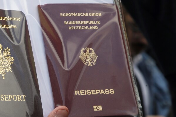 FILE - A person holds German and French, left, passports during a demonstration march to protest government plans to reform the education system, in Paris, France, Tuesday, May 19, 2015. Official data shows another big increase in the number of people gaining German citizenship last year. According to the figures released Tuesday, May 28, 2024, large numbers of people from Syria helped push naturalizations up to their highest level since at least 2000. (AP Photo/Francois Mori, File)