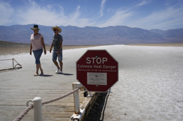 A sign warns visitors of extreme heat danger at Badwater Basin, Sunday, July 16, 2023, in Death Valley National Park, Calif. Death Valley's brutal temperatures come amid a blistering stretch of hot weather that has put roughly one-third of Americans under some type of heat advisory, watch or warning. (AP Photo/John Locher)