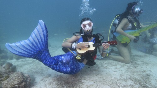 En esta foto proporcionada por Florida Keys News Bureau, Tamara Bredova, a la izquierda, con un disfraz de sirena, finge tocar un ukelele bajo el agua, el sábado 8 de julio de 2023, mientras que Kelly Angel, a la derecha, toca una guitarra falsa en Lower Keys Underwater. Festival de Música en el Santuario Marino Nacional de los Cayos de Florida cerca de Big Pine Key, Florida.  Varios cientos de buceadores y buceadores se sumergieron a lo largo de una sección de la única barrera de coral viviente en los Estados Unidos continentales para escuchar una transmisión de cuatro horas de una estación de radio local, canalizada bajo el mar para promover la preservación de los arrecifes de coral.  Kelly Angel está a la derecha.  (Frazier Nivens/Oficina de noticias de los Cayos de Florida vía AP)