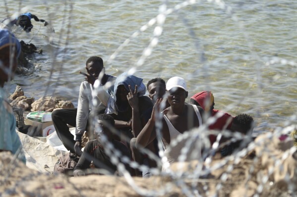 Migrants gather in an area near the Libyan-Tunisia border, as Libyan security forces and Libyan Red Cross workers distribute food aid to them on Sunday, July 23, 2023. (AP Photo/Yousef Murad, file)