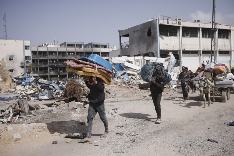 Palestinians carry their belongings after visiting their houses destroyed in the Israeli offensive on Khan Younis, Gaza Strip, Wednesday, March 6, 2024. (AP Photo/Mohammed Dahman)