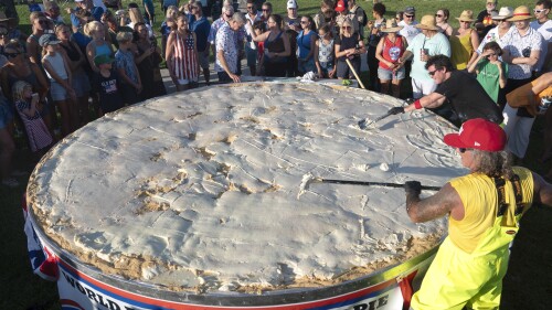 In this photo provided by the Florida Keys News Bureau, chefs Paul Menta, front right and David Sloan, back right, put finishing touches on a gargantuan Key lime pie created for a 200th Florida Keys birthday celebration Monday, July 3, 2023, on Big Pine Key, Fla. The festivities marked the anniversary of the Florida Territorial Legislature’s establishment of Monroe County on July 3, 1823, and celebrated its history. The pie, which organizers intend to certify as a world record, measured more than 13 feet (4 meters) in diameter. (Andy Newman/Florida Keys News Bureau via AP)