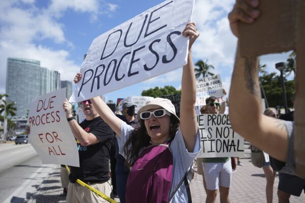 People hold signs and chant slogans during a protest against the Trump administration, Saturday, April 19, 2025, in Miami. (AP Photo/Lynne Sladky, File)