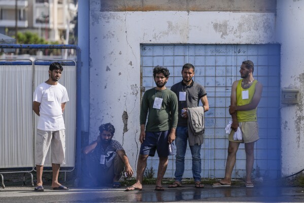 FILE - Survivors of a shipwreck stand outside a warehouse at the port in Kalamata town, about 240 kilometers (150miles) southwest of Athens, Greece on June 15, 2023. The international rights groups Amnesty International and Human Rights Watch allege on Thursday, Dec. 14, 2023, that Greek authorities have failed to properly investigate allegations by some survivors that the rescue mission had been mishandled. (AP Photos/Thanassis Stavrakis, File)