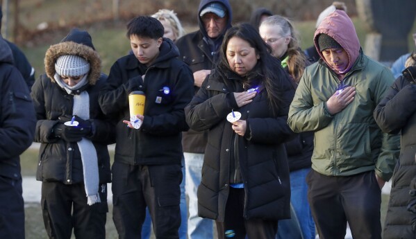 Family and friends of missing 3-year-old Elijah Vue pause during a vigil for him at Walsh Field, Saturday, March 16, 2024, in Two Rivers, Wis. Vue has been missing for more than 25 days. (Gary C. Klein/The Sheboygan Press via AP)