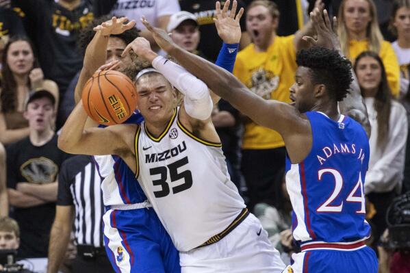 Missouri's Noah Carter, center, fights his way between Kansas' K.J. Adams Jr., right, and Jalen Wilson, left, during the first half of an NCAA college basketball game Saturday, Dec. 10, 2022, in Columbia, Mo. (AP Photo/L.G. Patterson)