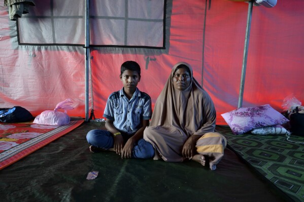 Rohingya refugee Rahena Begum, right, and her 13-year-old son, Noor Shahed, pose for a photograph at a temporary shelter in Meulaboh, Indonesia, on Thursday, April 4, 2024. They were among 75 people rescued in March from atop the overturned hull of a boat that capsized off Indonesia's coast. Dozens of others, including Rahena's 9-year-old daughter and 12-year-old son, died. (AP Photo/Reza Saifullah)