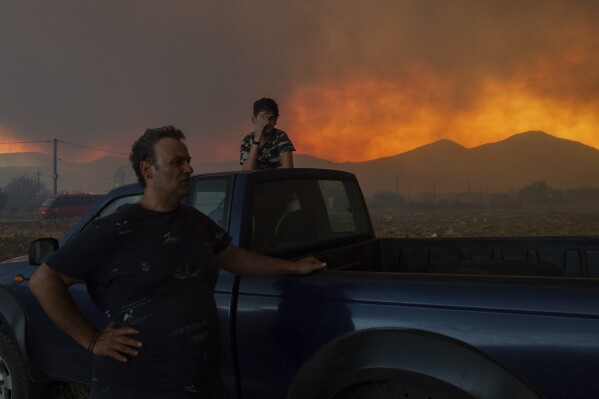 Local residents watch the wildfire in Avantas village, near Alexandroupolis town, in the northeastern Evros region, Greece, Monday, Aug. 21, 2023. Gale-force winds are fanning the flames of wildfires across Greece, including 53 new blazes that broke out early Monday amid hot, dry and windy weather that has sucked moisture from vegetation. (AP Photo/Achilleas Chiras)