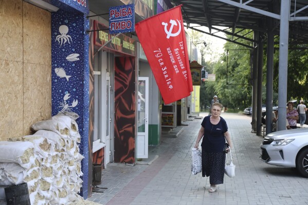A woman walks past a shop decorated with a replica of a victory banner prior to local elections in Donetsk, the capital of Russian-controlled Donetsk region, eastern Ukraine, on Thursday, Sept. 7, 2023. (AP Photo)