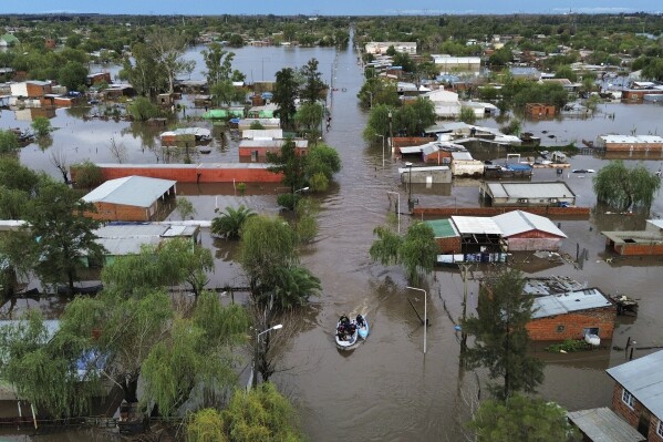 Boats move through flooded streets after heavy rains in Campana, Argentina, Saturday, May 17, 2025. (AP Photo/Rodrigo Abd)