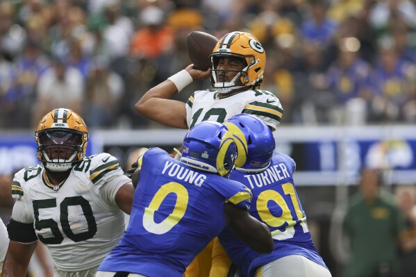 Green Bay Packers quarterback Jordan Love (10) is grabbed by Los Angeles Rams linebacker Byron Young (0) and defensive tackle Kobie Turner (91) during the first half of an NFL football game Sunday, Oct. 6, 2024, in Inglewood, Calif. (AP Photo/Ryan Sun)