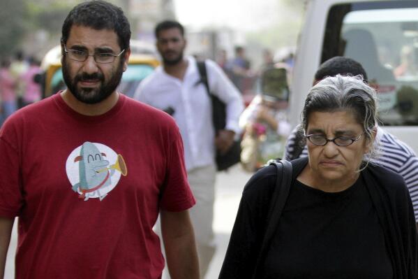 FILE - Alaa Abdel Fattah, left, a leading Egyptian pro-democracy activist walks with his mother Laila Soueif, a university professor who is an also an activist, outside a court, in Cairo, Egypt, Oct. 26, 2014. The family of Abdel Fattah who has been imprisoned for over three and a half years said Monday, April 11, 2022, that he has gained British citizenship, through his mother, who was born in London. He spent most of the past decade in prison, and has become a symbol of Egypt’s return to autocratic rule. (AP Photo/Hussein Tallal, File)