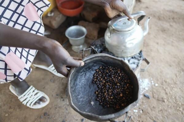 A food vendor fries roasted coffee beans in Yambio, South Sudan on Monday, Feb. 17, 2025. (AP Photo/Brian Inganga)