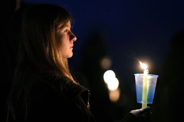 A local resident prays during a candlelight vigil following a shooting at Perry High School, Thursday, Jan. 4, 2024, in Perry, Iowa. (AP Photo/Charlie Neibergall)