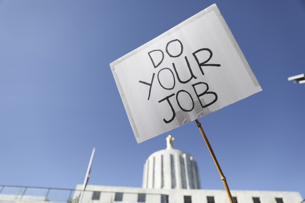 FILE - An attendee holds up a sign during a rally calling for an end to the Senate Republican walkout at the Oregon State Capitol in Salem, Ore., on May 11, 2023. Funding for schools, literacy programs and special education teachers in Oregon — a state where 60% of third graders are not reading at grade level — could be jeopardized by a Republican walkout that has stalled hundreds of bills and ground the Legislature to a partisan halt for over a month. (AP Photo/Amanda Loman, File)