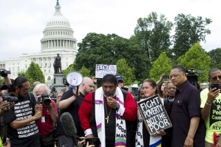 
              FILE - In this Saturday, June 23, 2018 file photo, Rev. Dr William Barber II accompanied by Rev. Dr. Liz Theoharis and Rev. Jesse Jackson speaks to the crowd outside of the U.S. Capitol during a Poor People's Campaign rally at The National Mall in Washington. The Rev. William Barber, a leader of the Poor People's Campaign says the social justice movement is planning bus tours of poverty-stricken areas in more than 20 states to refocus the country on its true emergencies. (AP Photo/Jose Luis Magana, File)
            
