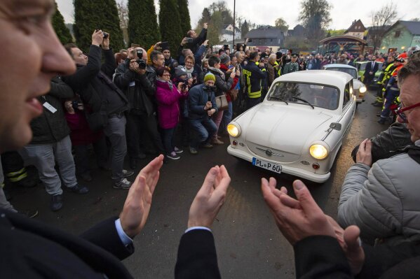 People welcome the legendary GDR cars Trabant (Trabi), during a symbolic wall opening, celebrating the 30th anniversary of the falling wall in the outdoor area of the German-German museum in Moedlareuth, Germany, Saturday, Nov. 9, 2019. Moedlareuth, named 'Little Berlin', was the symbol of a divided village along the borderline between East and West Germany. The border ran straight through the little village. (AP Photo/Jens Meyer)