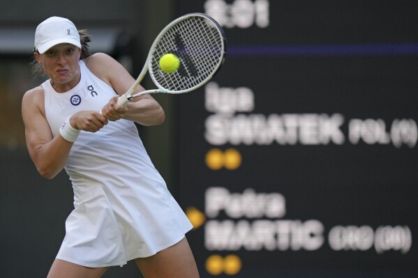 Poland's Iga Swiatek returns to Croatia's Petra Martic in a women's singles match on day five of the Wimbledon tennis championships in London, Friday, July 7, 2023. (AP Photo/Alberto Pezzali)