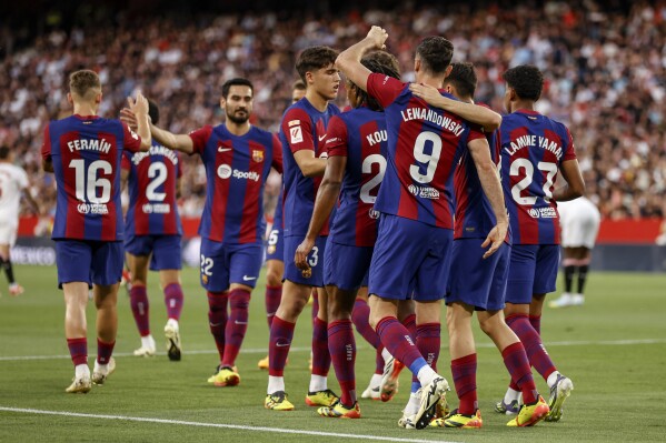 Barcelona's Robert Lewandowski, second right, celebrates with teammates after scoring his side's first goal during a Spanish La Liga soccer match between Sevilla and FC Barcelona at the Ramon Sanchez Pizjuan stadium in Seville, Spain, Sunday, May 26, 2024. (AP Photo/Fermin Rodriguez)