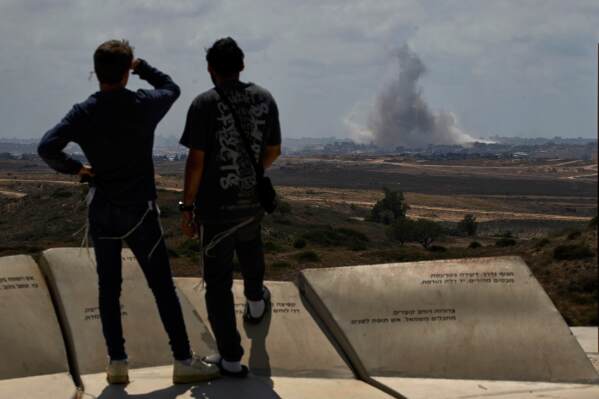 People watch smoke rising to the sky after an explosion in the Gaza Strip as they visit a sightseeing area in Sderot, southern Israel, Thursday, May 22, 2025. (AP Photo/Leo Correa)