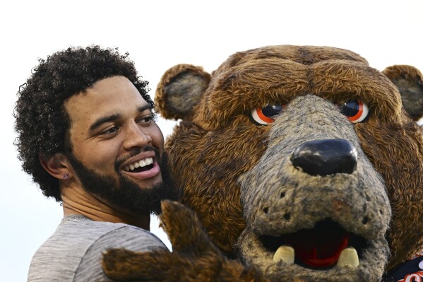 Chicago Bears quarterback Caleb Williams gets a hug from the mascot during warmups before an NFL exhibition Hall of Fame football game against the Houston Texans, Thursday, Aug. 1, 2024, in Canton, Ohio. (AP Photo/David Dermer)