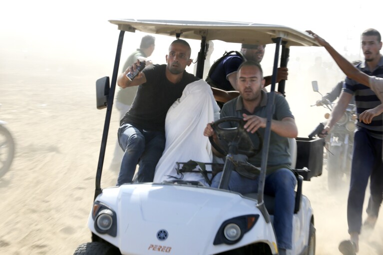 Palestinians transport a captured Israeli civilian from Kibbutz Kfar Azza into the Gaza Strip on Saturday, Oct. 7, 2023. (AP Photo/Hatem Ali)