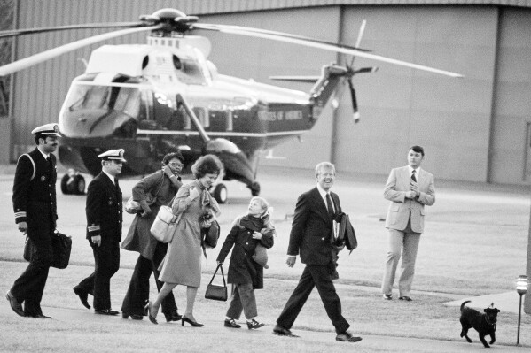 FILE President Jimmy Carter, second from right, arrives at Camp David, Md., with first lady Rosalynn Carter and daughter Amy Carter, center, on Friday, Feb. 25, 1977, along with Mary Fitzpatrick, Amy's nursemaid, third from left, and two unidentified military aides as they walk toward the house at the presidential retreat in the Maryland mountains for the first time. Rosalynn Carter used her powerful posts to address injustices as her husband rose in politics, especially those imposed as part of the racist Jim Crow system that prevailed in Georgia. The most personal of those cases involved Mary Prince Fitzpatrick, who went to Washington as White House nanny to Amy Carter with a felony murder conviction still on her record. (AP Photo/Charles Tasnadi, File)