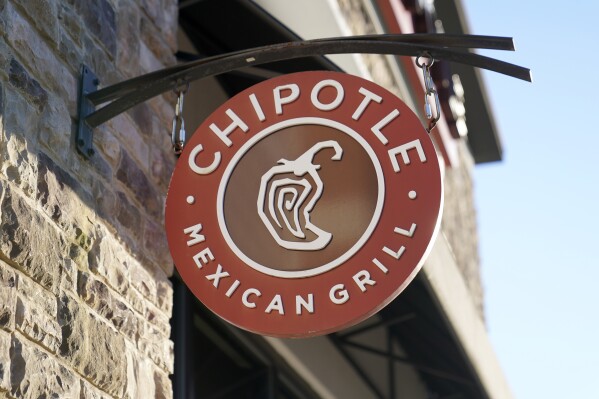 FILE - The Chipotle Mexican Grill logo hangs outside a restaurant location, Dec. 20, 2022. On Wednesday, Sept. 27, 2023, a federal agency sued the restaurant chain Chipotle, accusing it of religious harassment and retaliation after a manager at a Kansas location forcibly removed an employee's hijab, a headscarf worn by some Muslim women. (AP Photo/Steven Senne, File)