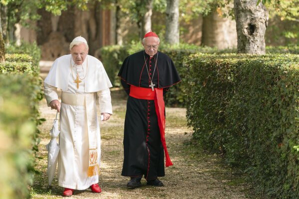 This image released by Netflix shows Jonathan Pryce as Cardinal Bergoglio, right, and Anthony Hopkins as Pope Benedict in a scene from "The Two Popes." (Peter Mountain/Netflix via AP)