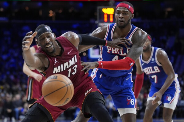 Miami Heat's Bam Adebayo (13) reaches for a loose ball as Philadelphia 76ers' Paul Reed defends during the first half of an NBA basketball game, Wednesday, Feb. 14, 2024, in Philadelphia. (AP Photo/Matt Rourke)