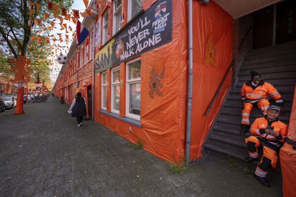Municipal workers take a break in a staircase as orange tarp, orange bunting, and Dutch national flags decorate Marktweg street in The Hague, Netherlands, Thursday June 13, 2024, one day ahead of the start of the Euro 2024 Soccer Championship. The Marktweg is one of several streets in the Netherlands that get an all-encompassing orange facelift during European Championships and World Cups when the national team, known as Oranje after the Dutch royal family and the color of their shirts, are playing. (AP Photo/Peter Dejong)