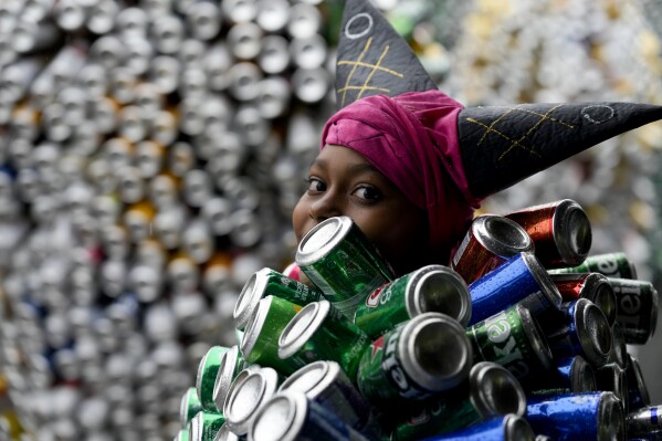A reveler wearing a costume made from beer and soda cans takes part in the 'Bloco da Latinha' street party Carnival parade in Madre de Deus, Brazil, Sunday, Feb. 11, 2024. (AP Photo/Eraldo Peres)