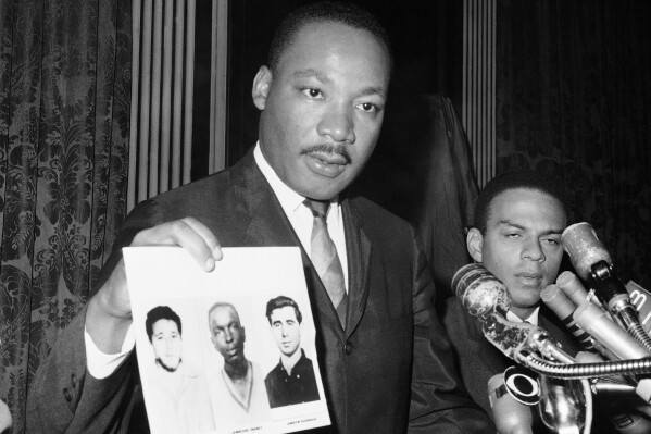 Civil rights leader Martin Luther King Jr. displays pictures of three civil rights workers, who were slain in Mississippi the summer before, from left Michael Schwerner, James Chaney, and Andrew Goodman, at a news conference Dec. 4, 1964, in New York, where he commended the FBI for its arrests in Mississippi in connection with the slayings. (AP Photo/JL, File)