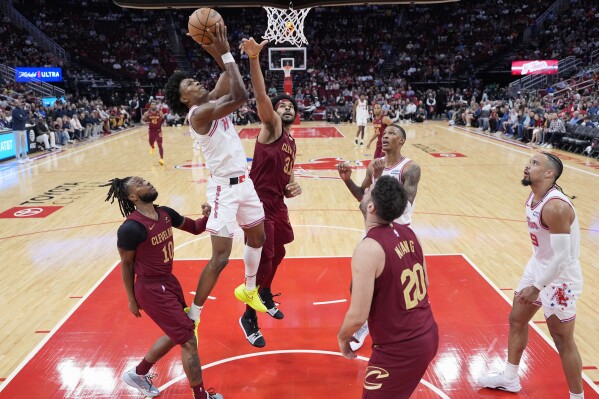 Houston Rockets' Amen Thompson, center left, goes up for a shot as Cleveland Cavaliers' Darius Garland (10) and Jarrett Allen (31) defend during the first half of an NBA basketball game Saturday, March 16, 2024, in Houston. (AP Photo/David J. Phillip)