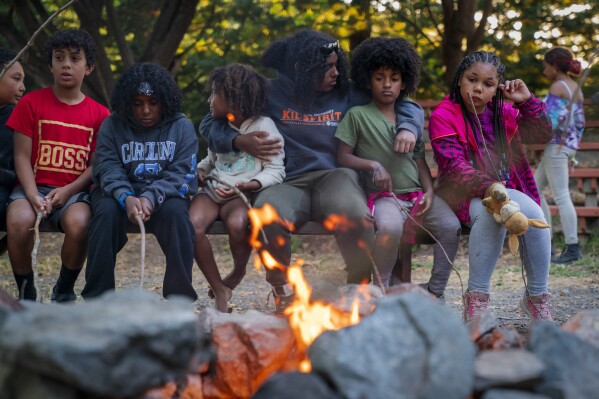 Zohara Grossman-Naples, 15, of Philomath, Oregon, center, hugs younger campers as they roast s'mores during a fire pit at Camp Be'chol Lashon, a sleepaway camp for Jewish children of color, Friday, July 28, 2023, in Petaluma, Calif., at Walker Creek Ranch. (AP Photo/Jacquelyn Martin)