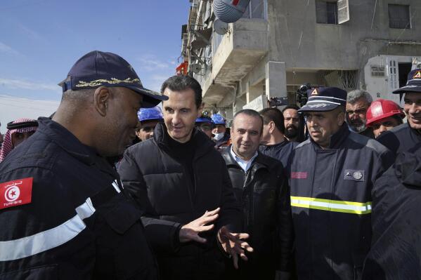 In this photo released by the official Syrian state news agency SANA, Syrian President Bashar Assad, second left, speaks with an Algerian rescue team at the site of destroyed buildings fallowing devastating earthquake, in Aleppo province, Syria, Friday, Feb. 10, 2023. Rescuers pulled several people alive from the shattered remnants of buildings on Friday, some who survived more than 100 hours trapped under crushed concrete in the bitter cold after a catastrophic earthquake slammed Turkey and Syria. (SANA via AP)