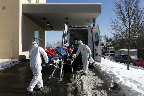 Medical workers move a covid-19 patient into an ambulance at a hospital overrun by the covid pandemic in Cheb, Czech Republic, Friday, Feb. 12, 2021. The Czech government has imposed a complete lockdown of the three hardest-hit counties to help contain the spread of a highly contagious variant of the coronavirus. The meeasures will became effective Friday for the two counties in western Czech Republic on the German border Cheb and Sokolov and another county in the northern part of the country Trutnov located on the border with Poland. (AP Photo/Petr David Josek)