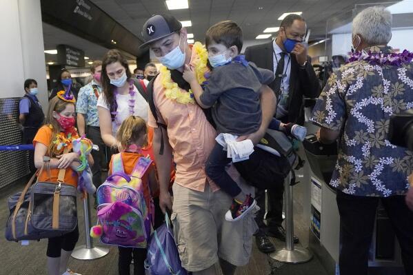 FILE - In this Oct. 15, 2020 file photo, Hawaii resident Ryan Sidlow carries his son Maxwell as their family boards a United Airlines flight to Hawaii at San Francisco International Airport in San Francisco. The Transportation Department is rolling out a “dashboard” to let travelers see at a glance which airlines help families with young children sit together at no extra cost. The announcement Monday, March 6, 2023 comes as the department works on regulations to prevent families from being separated on planes. (AP Photo/Jeff Chiu, File)