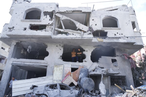 Palestinians stand inside the building destroyed in an Israeli airstrike in Nuseirat camp in the central Gaza Strip, Monday, Oct. 16, 2023. (AP Photo/Hatem Moussa)