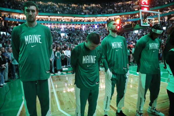 The Boston Celtics stand for a moment of silence for the victims of the shootings in Lewiston, Maine, before the team's NBA basketball game against the Miami Heat, Friday, Oct. 27, 2023, in Boston. (AP Photo/Michael Dwyer)