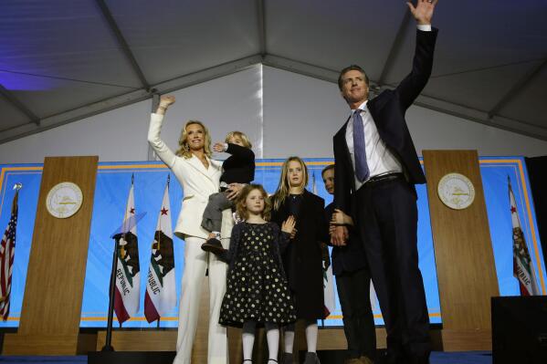 FILE - In this Monday, Jan. 7, 2019 file photo, California Governor Gavin Newsom, right, his wife, Jennifer Siebel Newsom, left, and children wave after taking the oath office during his inauguration as 40th Governor of California in Sacramento, Calif. Two of Gov. Gavin Newsom’s children have tested positive for the coronavirus and his office says the family is following “all COVID protocols.” A statement issued Friday, Sept. 17, 2021 says Newsom, his wife and two other children have since tested negative for the virus. (AP Photo/Rich Pedroncelli, File)