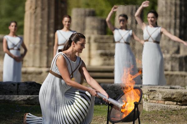 Greek actress Xanthi Georgiou, playing the role of the High Priestess, lights the torch during the lighting of the Olympic flame in Ancient Olympia, the birthplace of the ancient Olympics in southwestern Greece, Monday, Oct. 18, 2021. The flame will be transported by torch relay to Beijing, China, which will host the Winter Olympics from Feb. 4-20, 2022. (AP Photo/Thanassis Stavrakis)