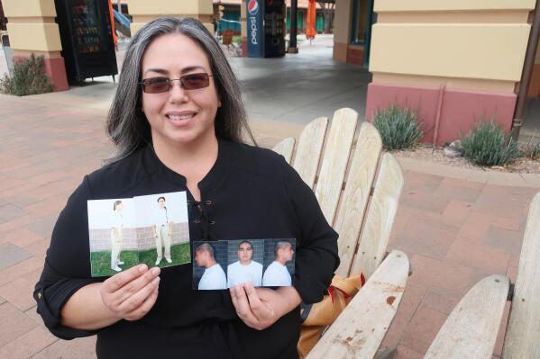 Carmen Briones holds up photos of her husband, Riley Briones Jr., who is serving life in prison, on Feb. 22, 2022, in Anthem, Ariz. Riley Briones' attorneys are asking a federal appeals court for another chance to argue his sentence should be cut short based on improvements he's made behind bars since being convicted in the 1994 death of Brian Patrick Lindsay when Briones was 17. (AP Photo/Felicia Fonseca)