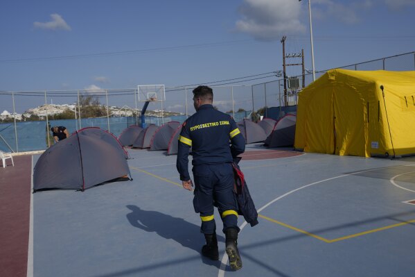 A firefighter walks next to tents set up at a basketball court to accommodate Fire Service rescuers as Greek authorities is taking emergency measures in response to intense seismic activity on the popular Aegean Sea holiday island of Santorini, southern Greece, Monday, Feb. 3, 2025. (AP Photo/Petros Giannakouris)
