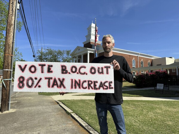 Rob Romeijn protests property taxes outside Rockdale County offices in Conyers, Ga., on April 23, 2024. Romeijn says the increase in the taxable value of his house is unfair, but future increases in taxable values could be curbed if Georgia voters approve a referendum in November. (AP Photo/Jeff Amy)