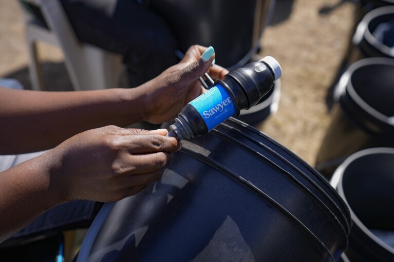 Water bucket filters are demonstrated by a member of the Bucket Ministry, a Christian nonprofit organization, in Athi River, Machakos county, Kenya, Tuesday, Oct. 17, 2023. (AP Photo/Brian Inganga)